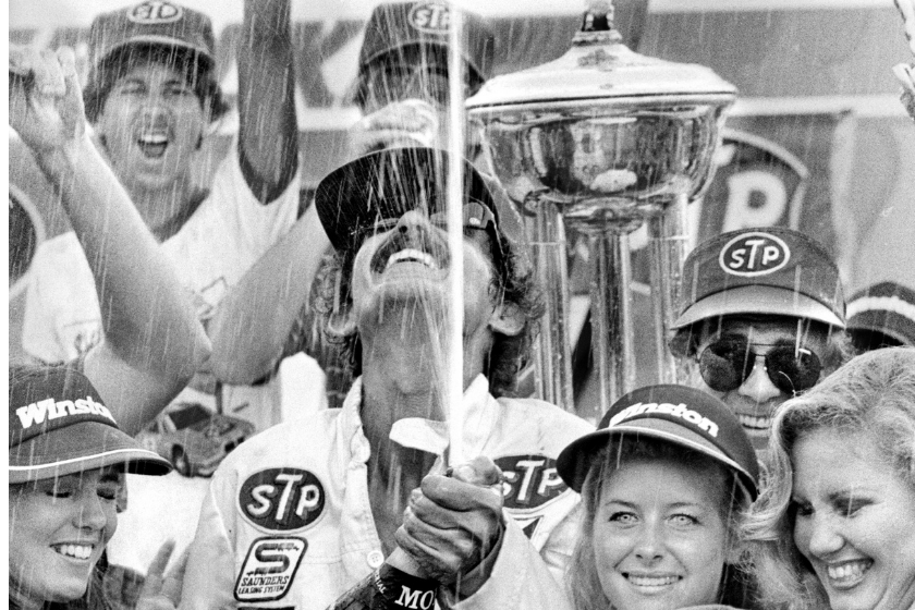 Richard Petty opens the traditional winner's champagne bottle in Victory Lane after winning the 1984 Firecracker 400 stock car race at Daytona International Speedway in Daytona Beach, Florida
