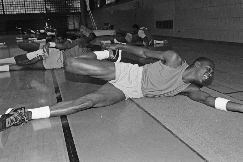 Michael Jordan smiles while he stretches on the floor of a gym