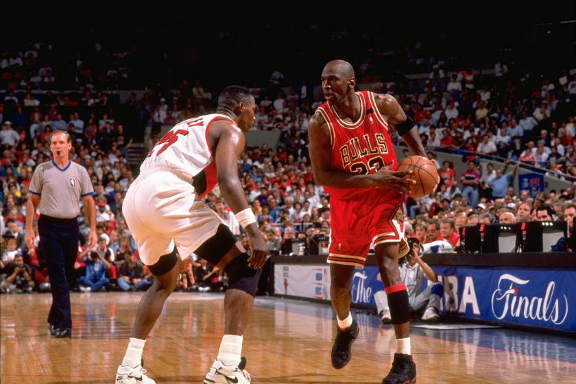 Michael Jordan holds the basketball away from a defender during a game.