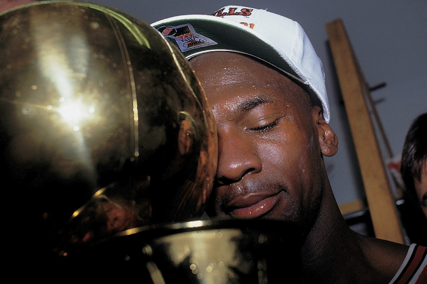 michael jordan closes his eyes and rests his head against a trophy