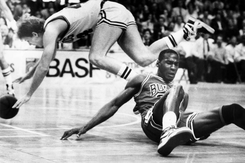 a player falls behind michael jordan, who is on the basketball floor