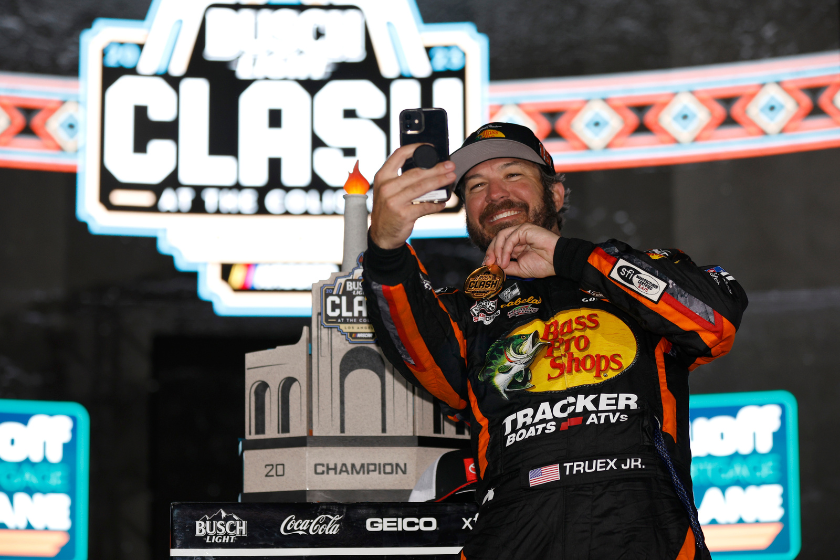 Martin Truex Jr. takes a selfie with the NASCAR Clash at the Coliseum trophy in victory lane after winning the 2023 Clash at Los Angeles Memorial Coliseum on February 05