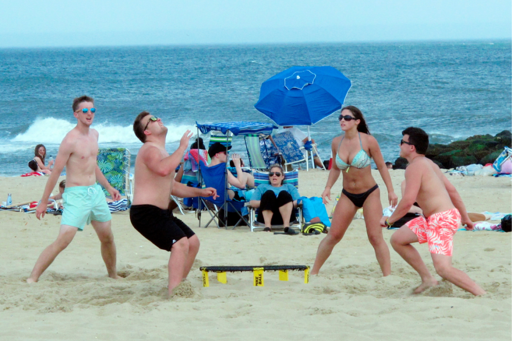 Friends play Spikeball on the beach.