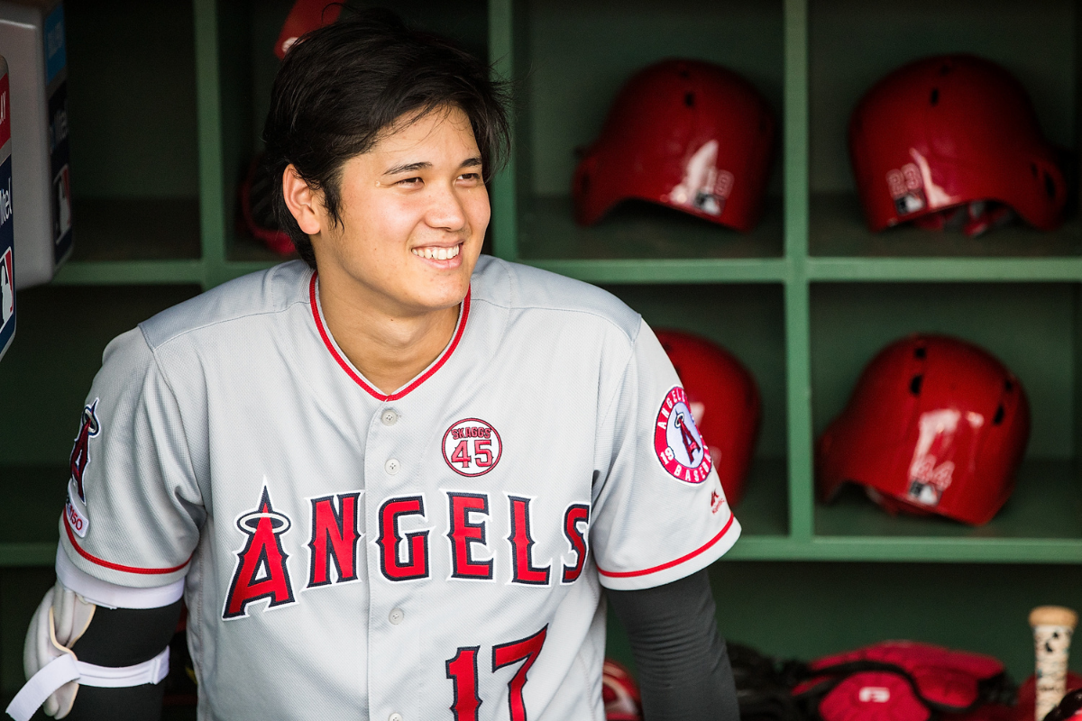 Shohei Ohtani smiles in the visitors dugout at Fenway Park.