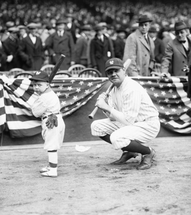 Babe Ruth squats next to a young fan in 1920.