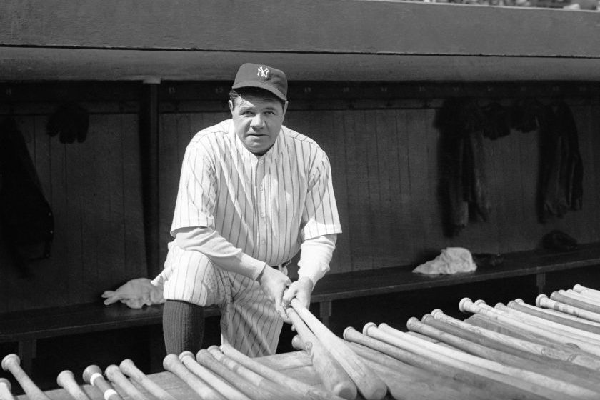 Babe Ruth holds a couple of baseball bats.