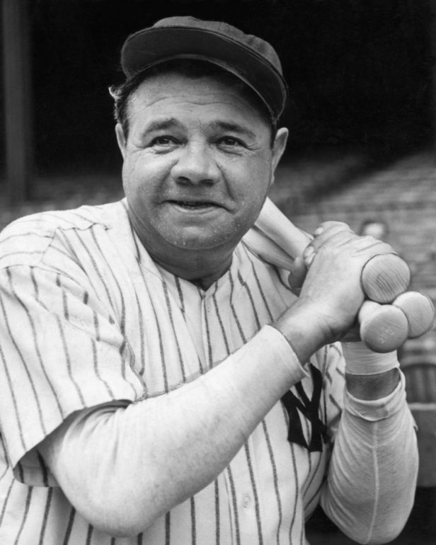 Babe Ruth holds a bat over his shoulder.