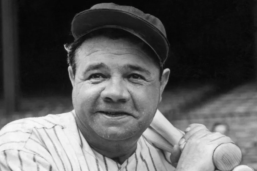 Babe Ruth holds a bat over his shoulder.