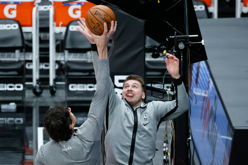 Boba Marjanovic holds a ball above Luka Doncic's head.