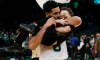 basketball player Jayson Tatum holds and kisses his son on the court after a game