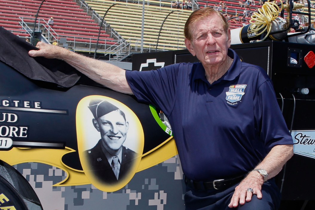 Bud Moore poses by a photograph of himself on the car of Ryan Newman