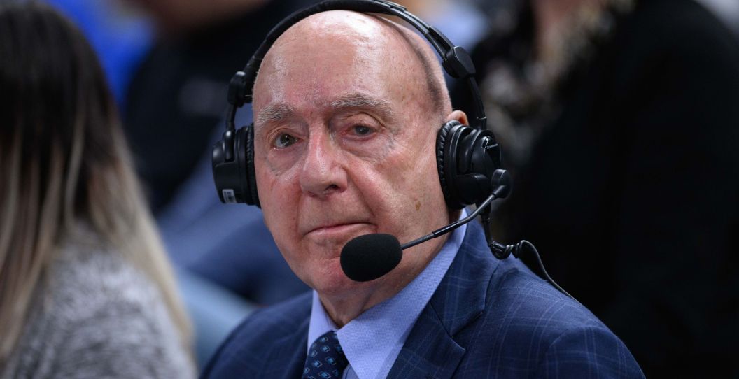 Dick Vitale looks on while wearing a headset at a college basketball game.
