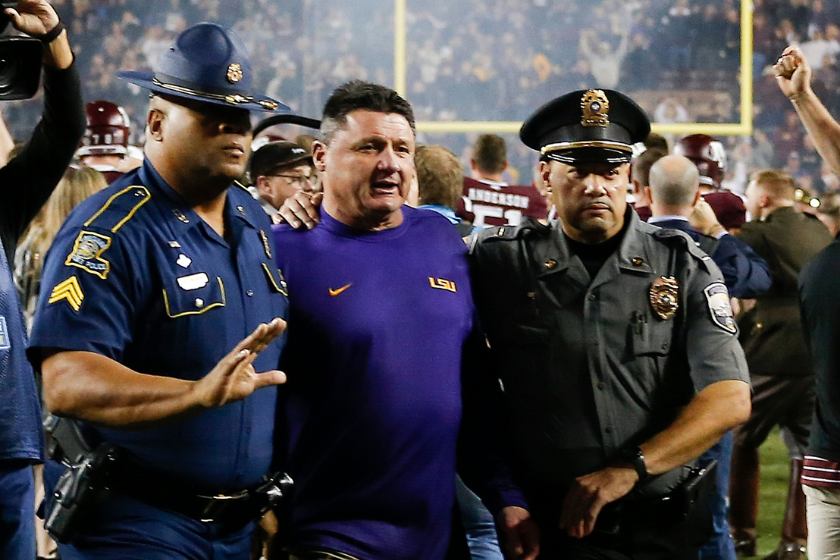 Head coach Ed Oregon of the LSU Tigers is escorted off the field after a 74-72 loss in 7 overtimes against the Texas A&M Aggies at Kyle Field