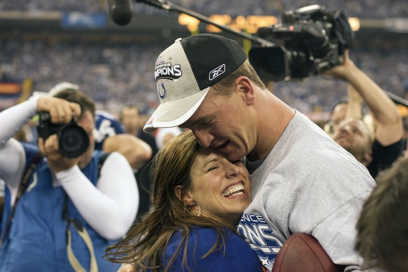 Peyton Manning and wife Ashley hug after winning a NFL playoff game.