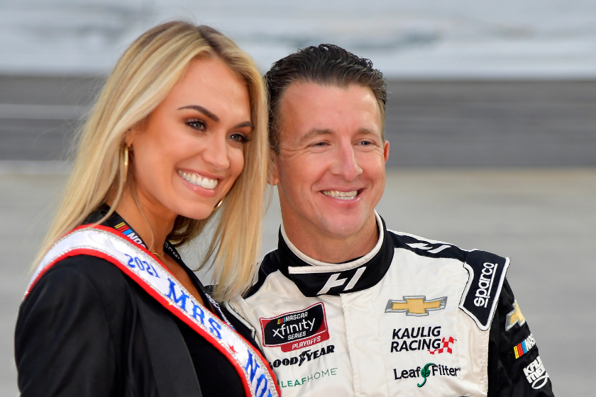 AJ Allmendinger and wife Tara Meador pose for photos on the grid prior to the NASCAR Xfinity Series Dead on Tools 250 at Martinsville Speedway on October 30, 2021 in Martinsville, Virginia