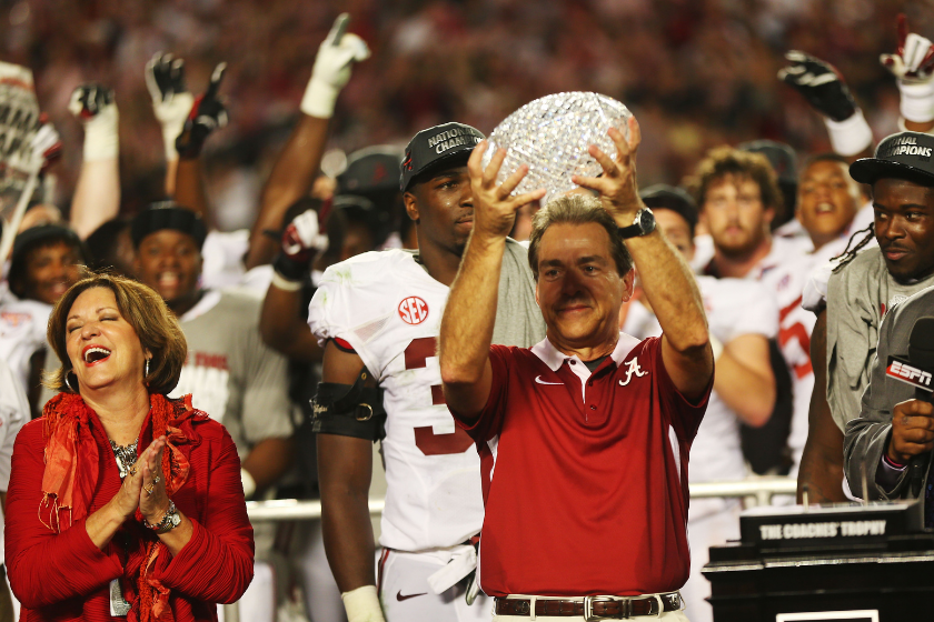 Alabama head coach lifts the BCS Coaches' Trophy with his wife Miss Terry.
