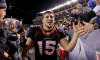 American football player Tim Tebow high-fives fans on the sidelines.