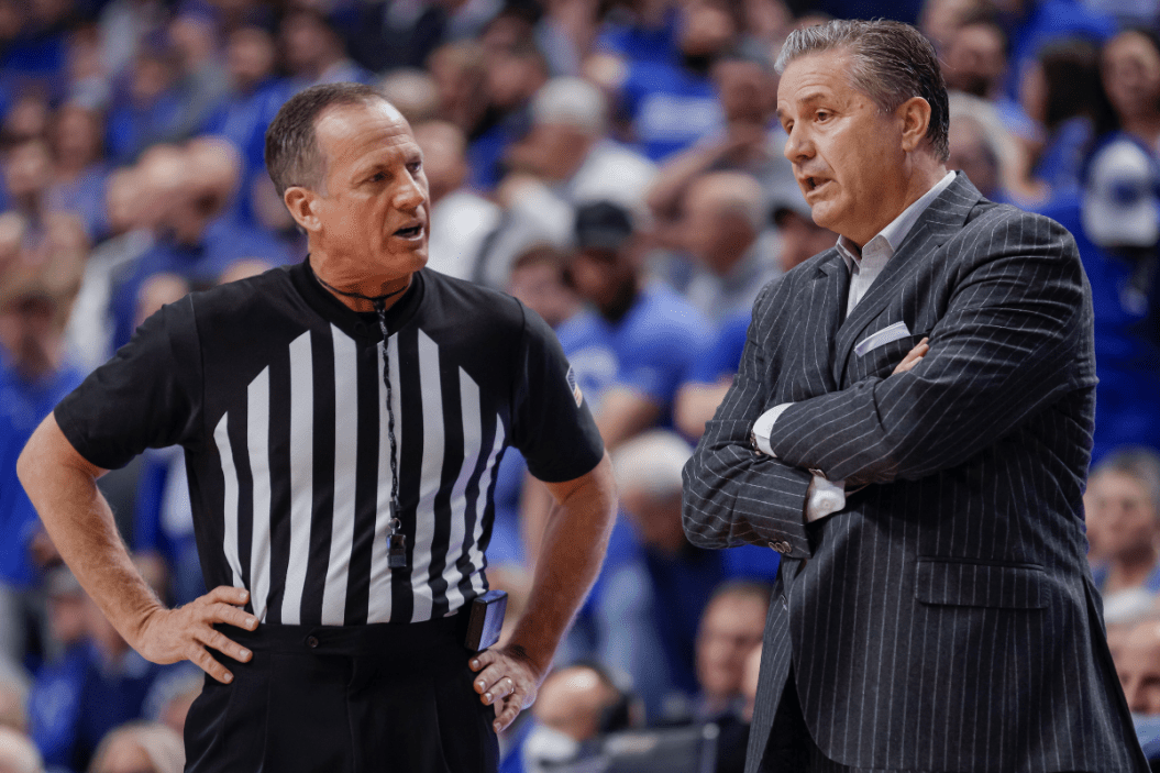 A referee talks with John Calipari during an NCAA basketball game.