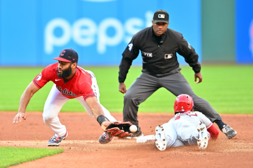 Second base umpire Alan Porter watches as shortstop Amed Rosario #1 of the Cleveland Guardians reaches for the throw as Andrew Velazquez #4 of the Los Angeles Angels slides in.