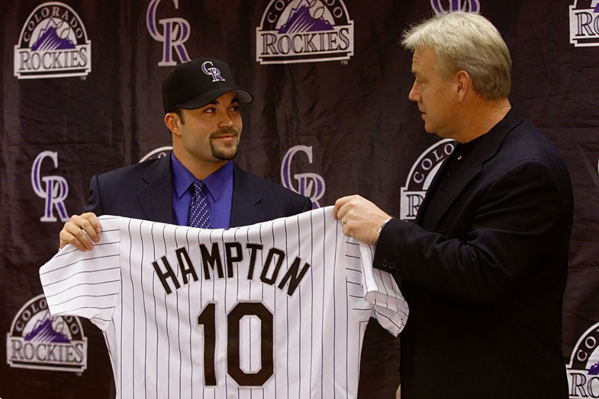 Pitcher Mike Hampton holds up his Colorado Rockies jersey and dons the team cap with the help of manager Buddy Bell during a press conference at Coors Field in Denver, Colorad