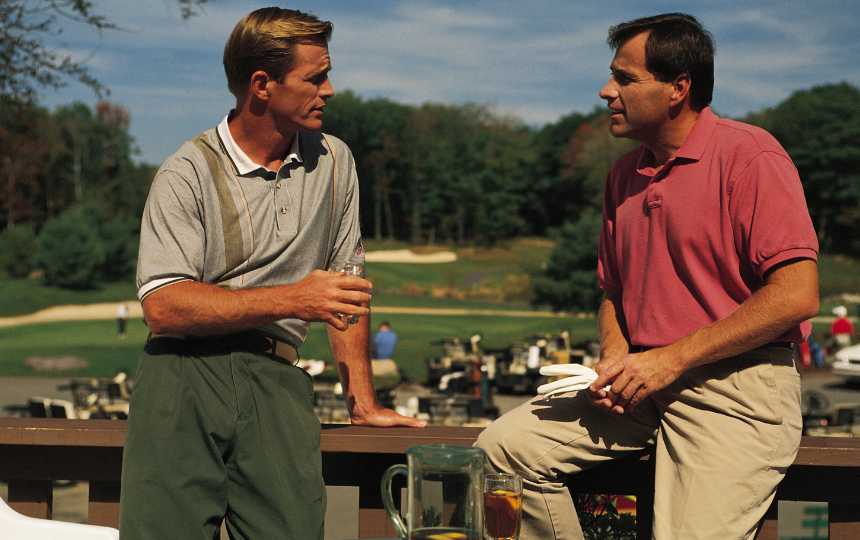 Two men enjoy drinks after playing a round of golf.