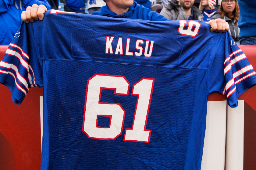 A fan holds up a Buffalo Bills Jersey with Bob Kalsu's name and number on it.
