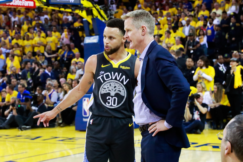 Steve Kerr and Steph Curry discuss a play during a Golden State Warriors game.