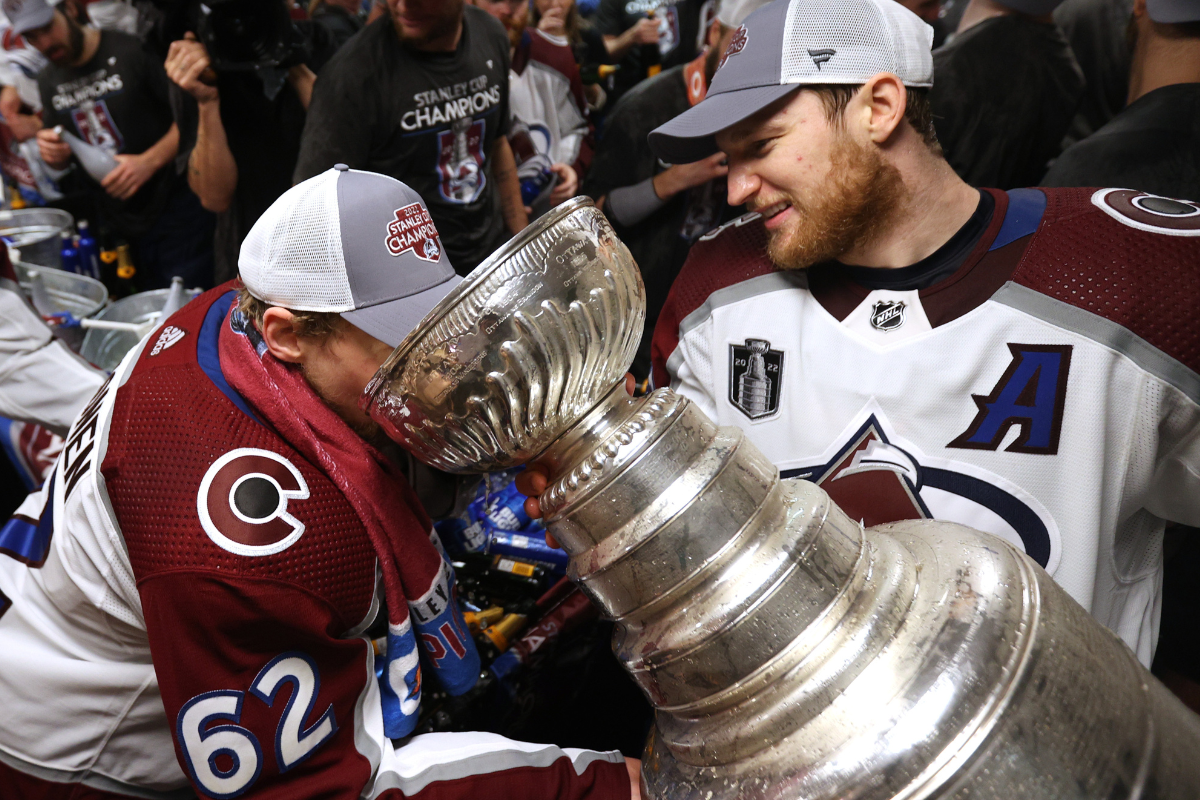 Nathan McKinnon helps Artturi Lehkonen take a sip from the Stanley Cup after the Avalanche dented it.