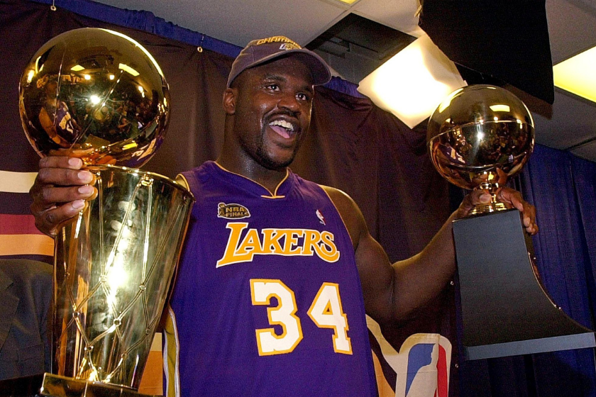 Shaquille O'Neal holds the MVP trophy (R) and the Larry O'Brian Championship trophy 