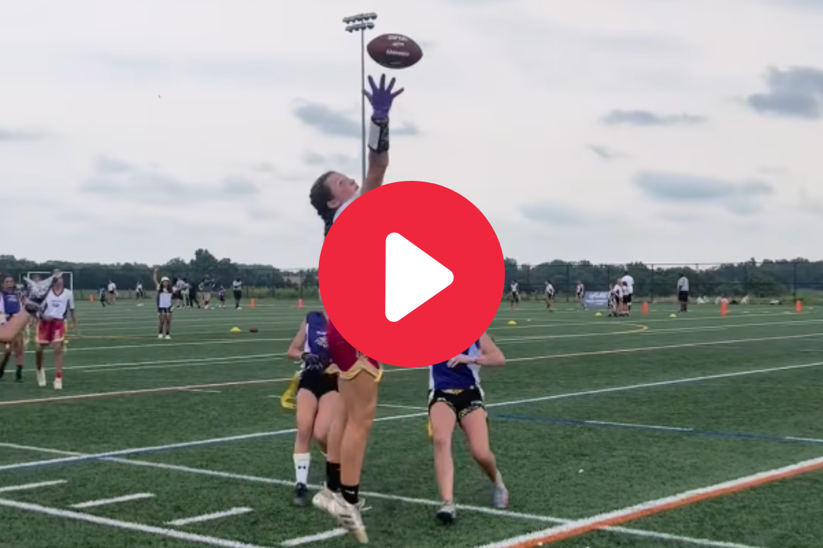 A girl makes a one-handed catch in a flag football game.