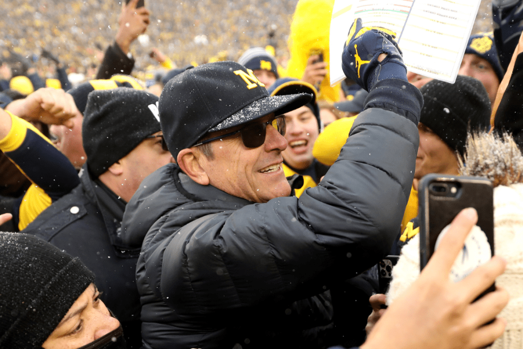Head Coach Jim Harbaugh of the Michigan Wolverines celebrates with fans after defeating the Ohio State Buckeyes
