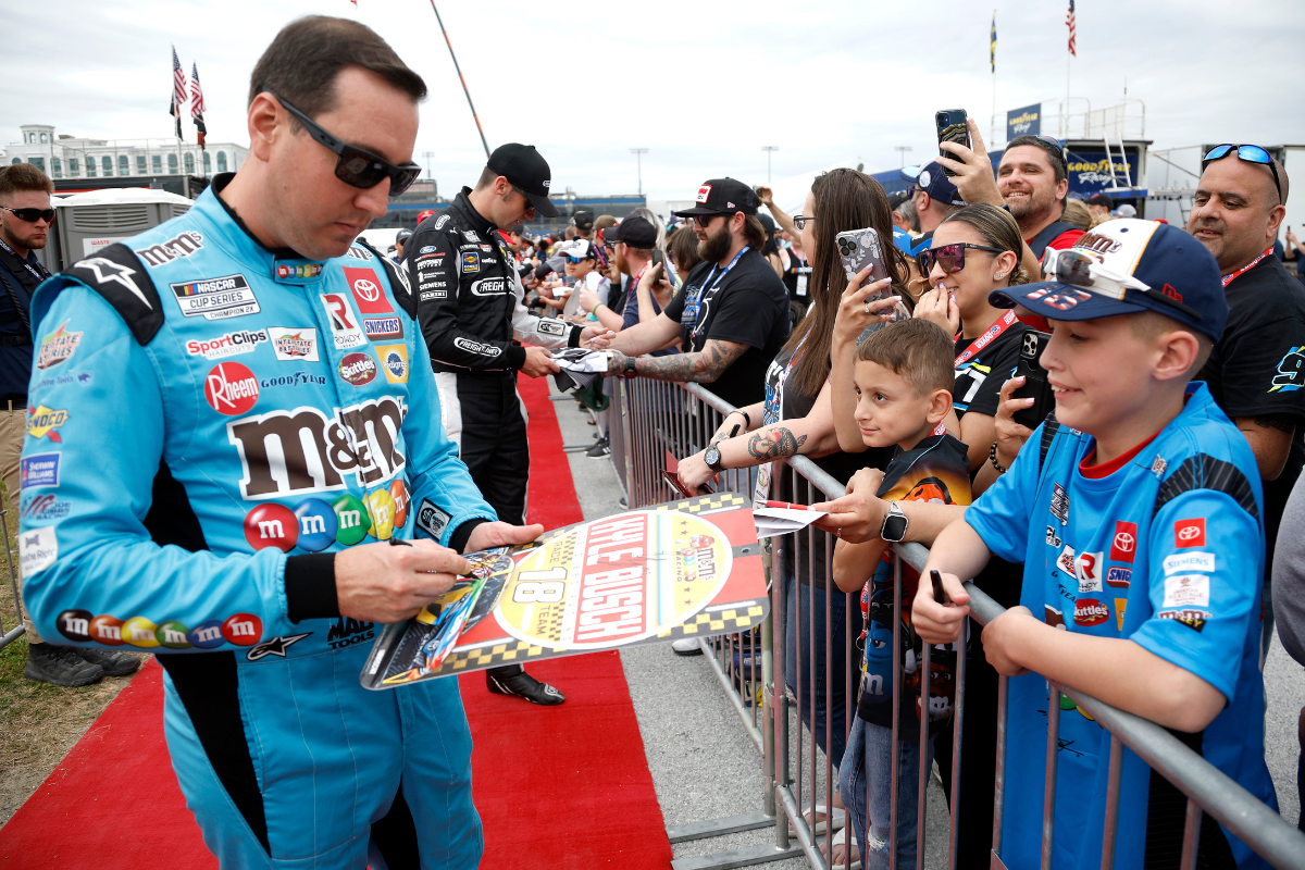 Kyle Busch signs memorabilia for a young NASCAR fan on the red carpet prior to the NASCAR Cup Series DuraMAX Drydene 400 presented by RelaDyne at Dover Motor Speedway on May 01, 2022