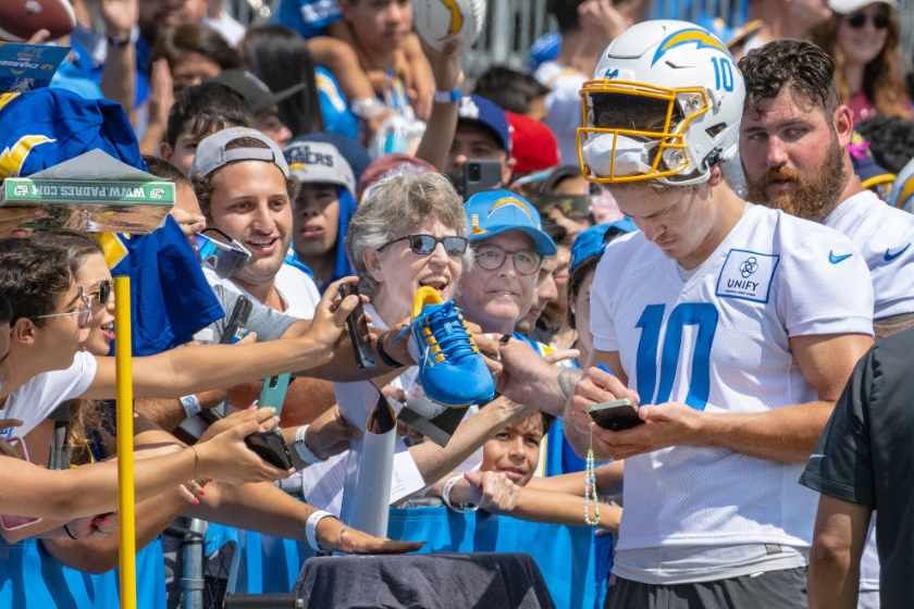 ustin Herbert, right, quarterback with the Los Angeles Chargers, signs autographs for fans at training camp