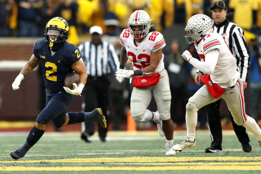 Blake Corum #2 of the Michigan Wolverines carries the ball as Steele Chambers #22 and Bryson Shaw #17 of the Ohio State Buckeyes defend