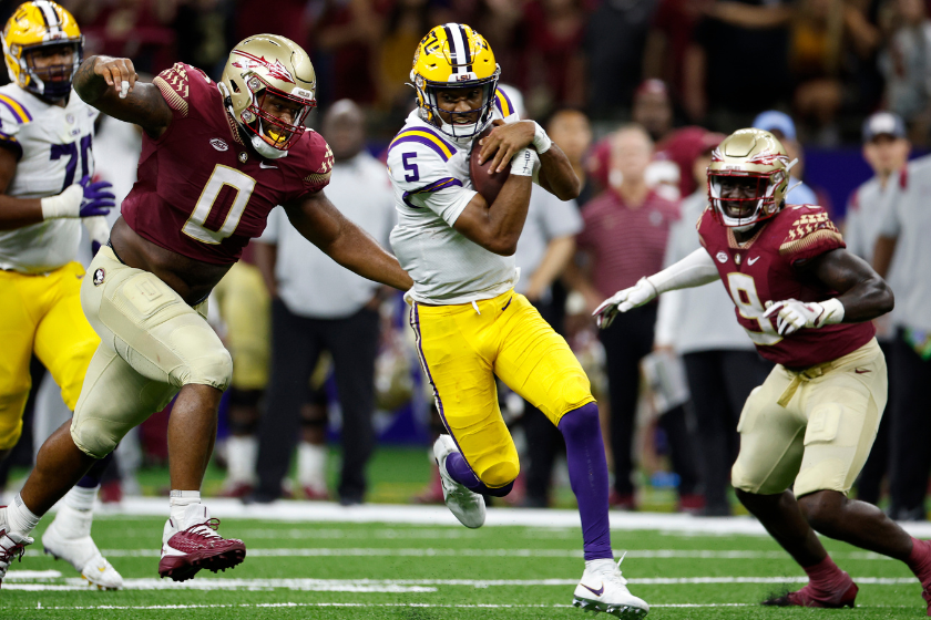Quarterback Jayden Daniels #5 of the LSU Tigers is tackled by defensive tackle Fabien Lovett #0 of the Florida State Seminoles 
