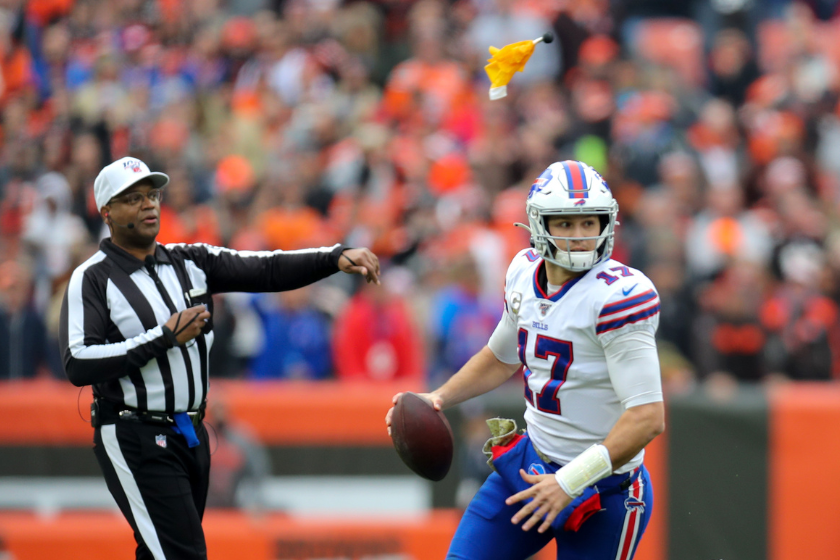 Buffalo Bills quarterback Josh Allen (17) rolls out of the pocket as an official throws a penalty flag for holding against the Bills