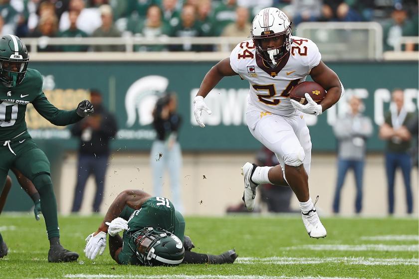 Mohamed Ibrahim #24 of the Minnesota Golden Gophers leaps after avoiding a tackle by Angelo Grose #15 of the Michigan State Spartans in the first half at Spartan Stadium