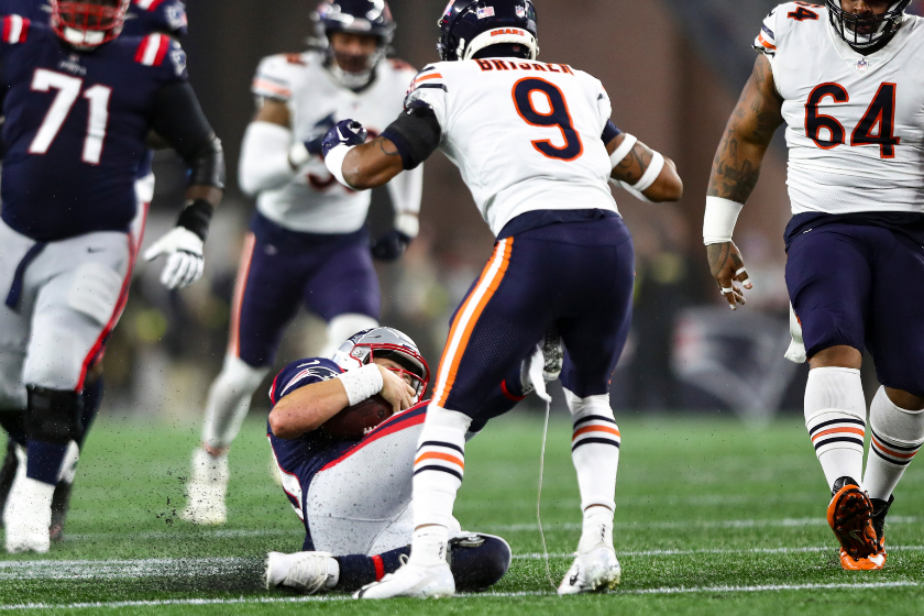 Mac Jones #10 of the New England Patriots slides and kicks Jaquan Brisker #9 of the Chicago Bears during the second quarter of an NFL football game