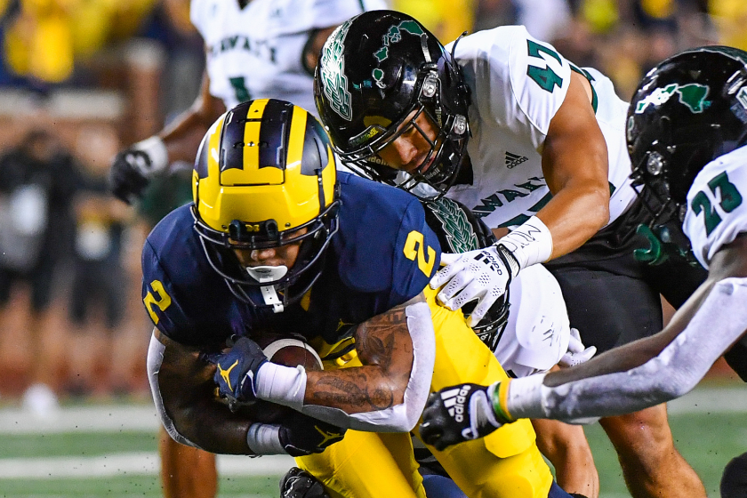 Noa Kamana #47 and Virdel Edwards II #23 of the Hawaii Rainbow Warriors attempt to tackle Blake Corum #2 of the Michigan Wolverines during the first half of a college football game at Michigan Stadium