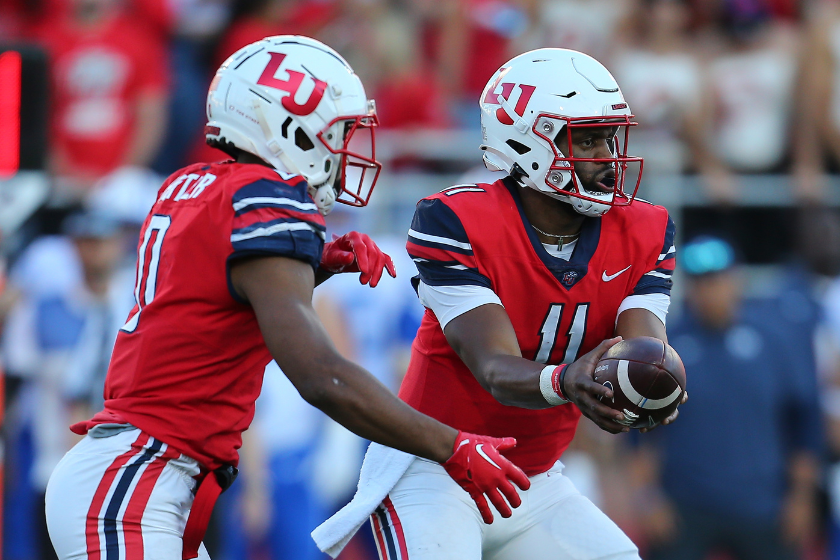 Liberty Flames quarterback Johnathan Bennett (11) hands the ball to running back Dae Dae Hunter (0) during a college football game against BYU