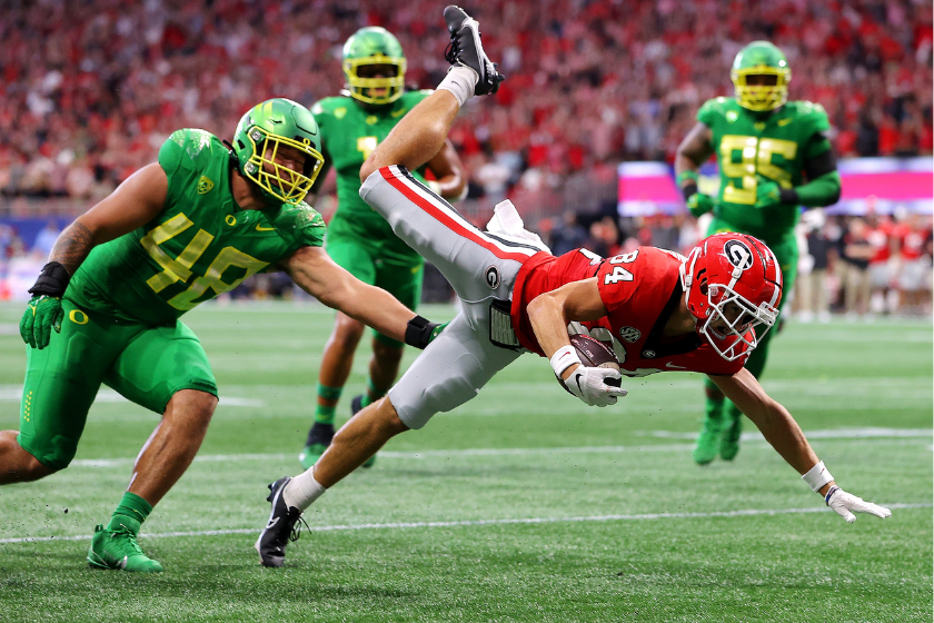  Ladd McConkey #84 of the Georgia Bulldogs leaps in an attempt to score past Treven Ma'ae #48 of the Oregon Ducks during the first quarter of the Chick-fil-A Kick-Off Game between Oregon and Georgia