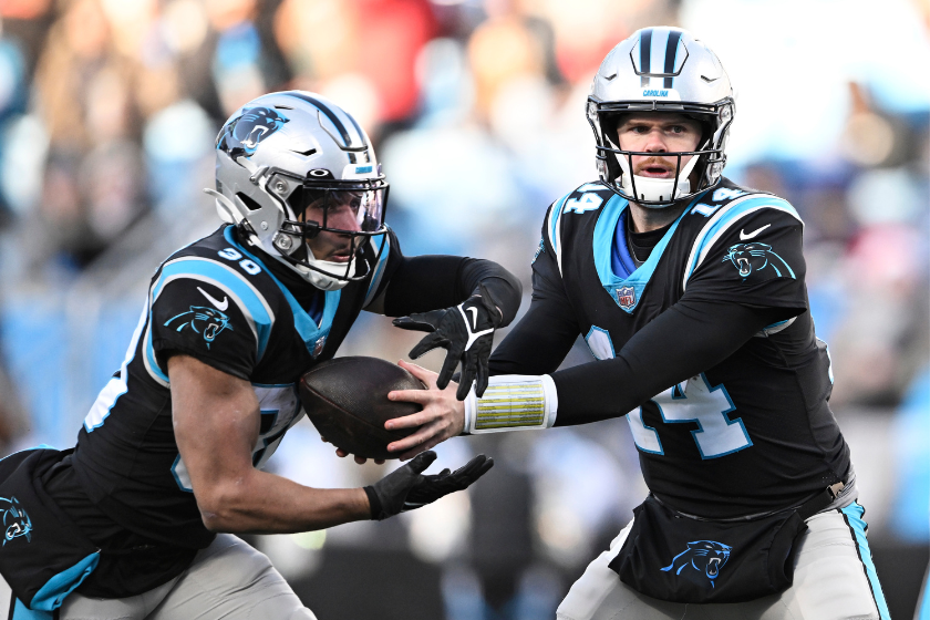Sam Darnold #14 hands the ball to Chuba Hubbard #30 of the Carolina Panthers against the Detroit Lions in the fourth quarter at Bank of America Stadium.