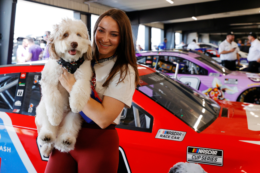 Bubba Wallace's girlfriend Amanda Carter poses with pet dog Asher in the garage area during qualifying for the 2021 Ally 400 at Nashville Superspeedway
