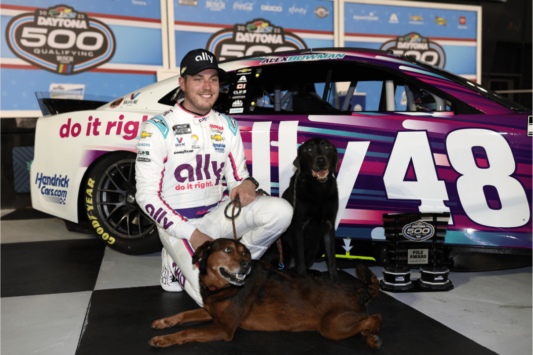 alex bowman poses with dogs, finn and roscoe, after winning the the Busch Light Pole Award at Daytona International Speedway on February 15, 2023