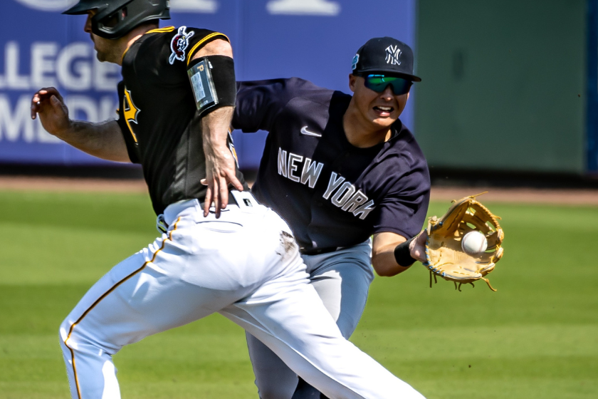  New York Yankees' Anthony Volpe fielding a ground ball hit by Travis Swaggerty of the Pittsburgh Pirates as Jason Delay runs by in the bottom of the 3rd inning during a spring training game
