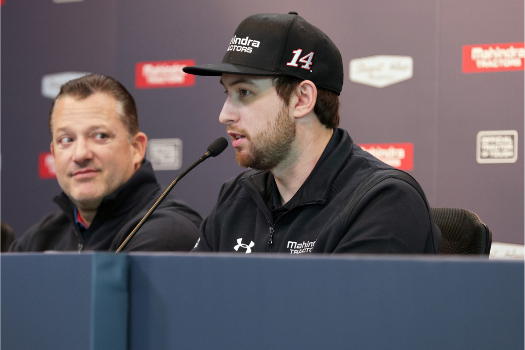 Chase Briscoe speaks as Tony Stewart looks on during a 2021 press event announcing a partnership between Stewart-Haas Racing and Mahindra Tractors at Indianapolis Motor Speedway