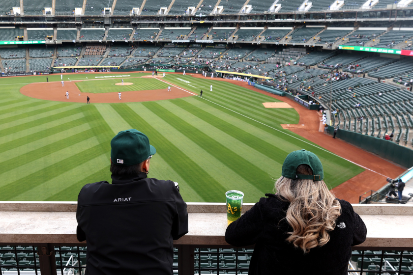 Two baseball fans watch the Oakland Athletics play the Texas Rangers in front of a small crowd at RingCentral Coliseum