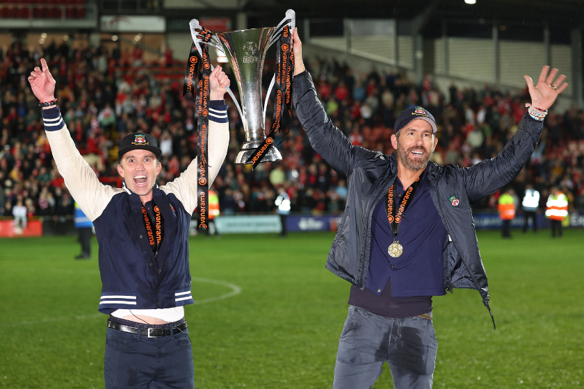Wrexham owners Rob McElhenney and Ryan Reynolds hold the Vanarama National League Trophy as Wrexham celebrate promotion back to the English Football League during the Vanarama National League match between Wrexham and Boreham Wood