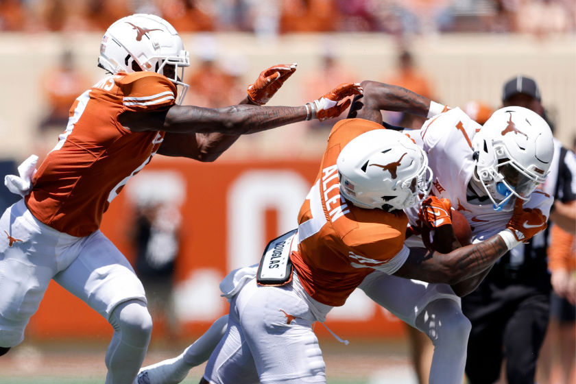 Xavier Worthy #1 of the Texas Longhorns is tackled by B.J. Allen Jr. #7 and Terrance Brooks #8 during the Texas Football Orange-White Spring Football Gam