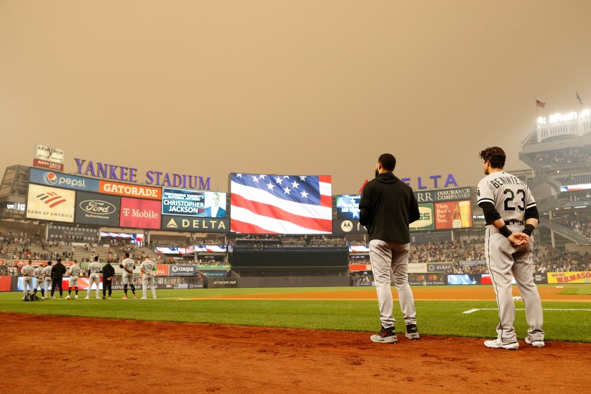 Yankees players stand during the national anthem with smoke above them.